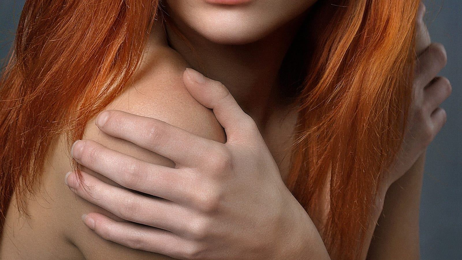 Woman with long, full, voluminous red-brown hair in soft light