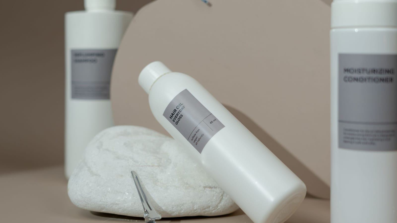 Sulfate-free cleanser and conditioner bottles with a hair clip on a neutral counter