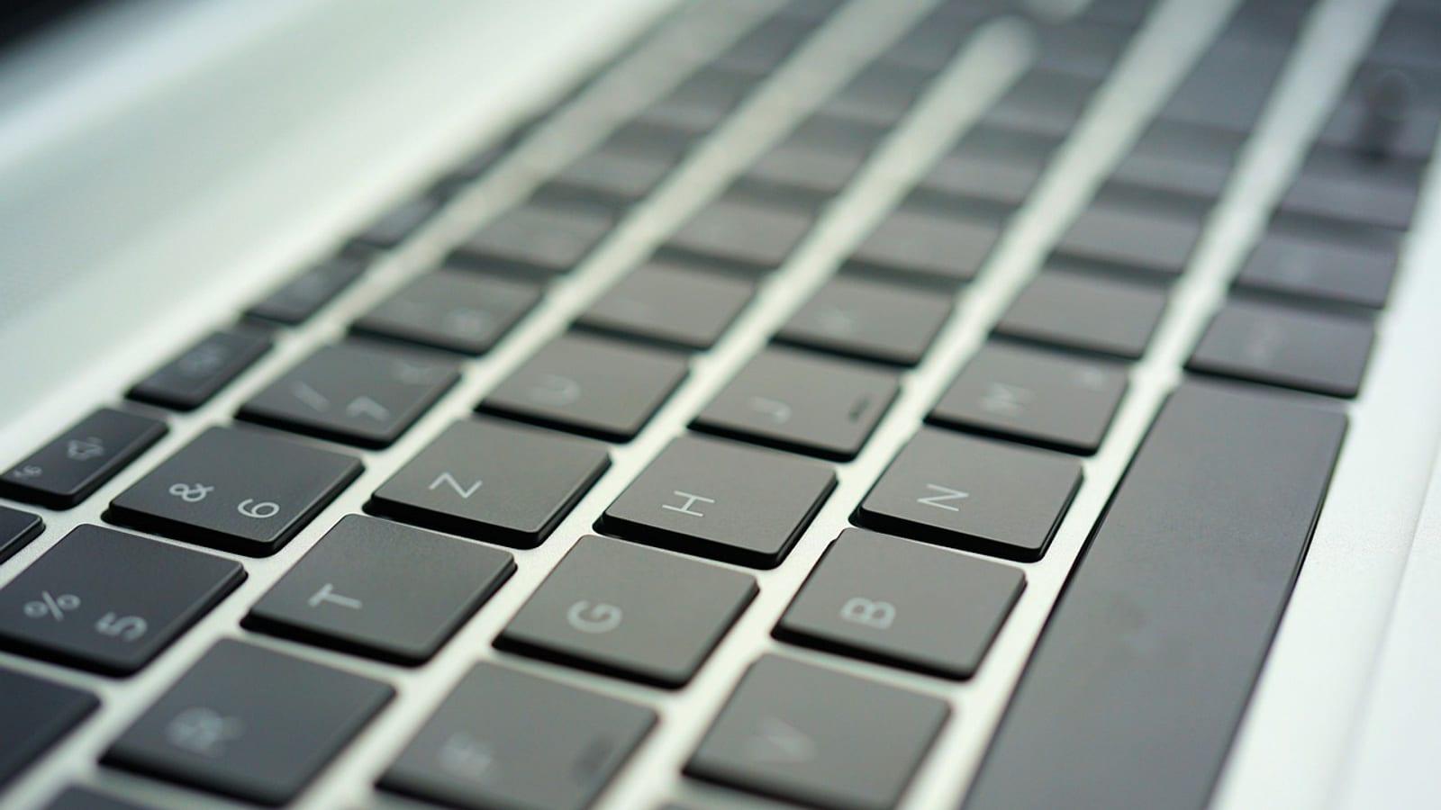 Close-up of a silver laptop keyboard photographed at an angle in soft light