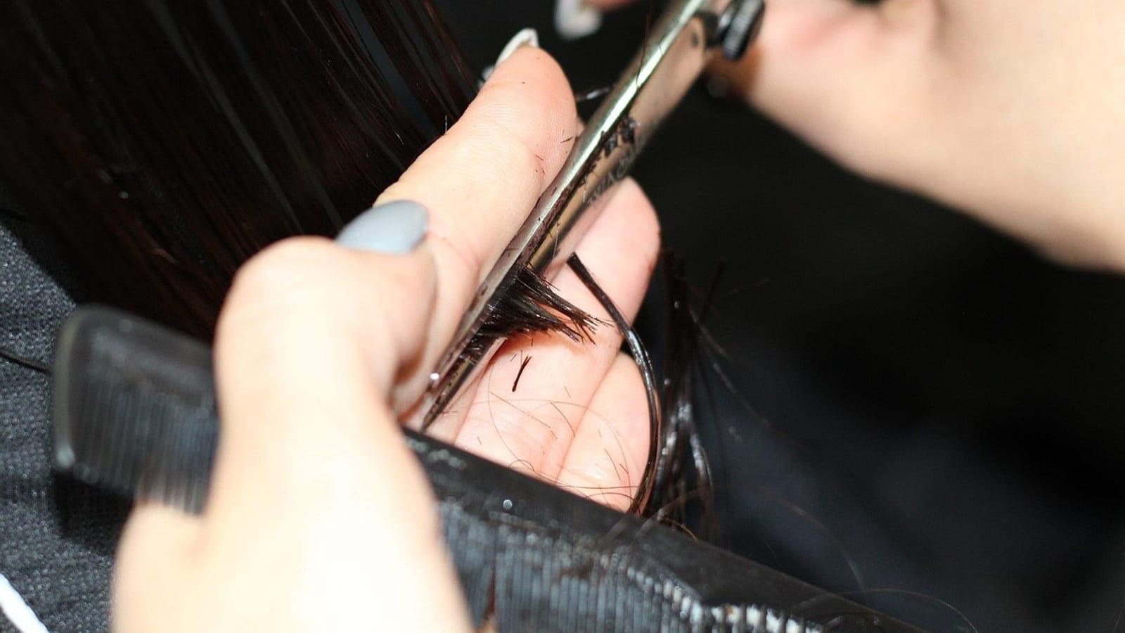 Close-up of scissors trimming the ends of dark hair