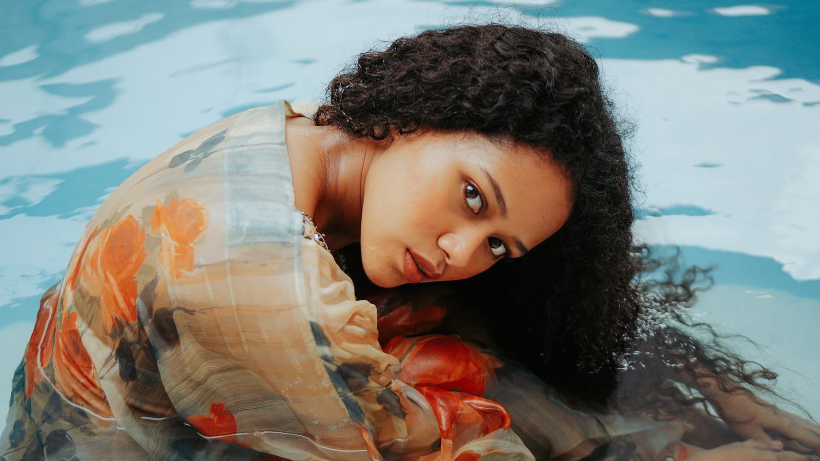 Woman with wet dark curls resting in a swimming pool