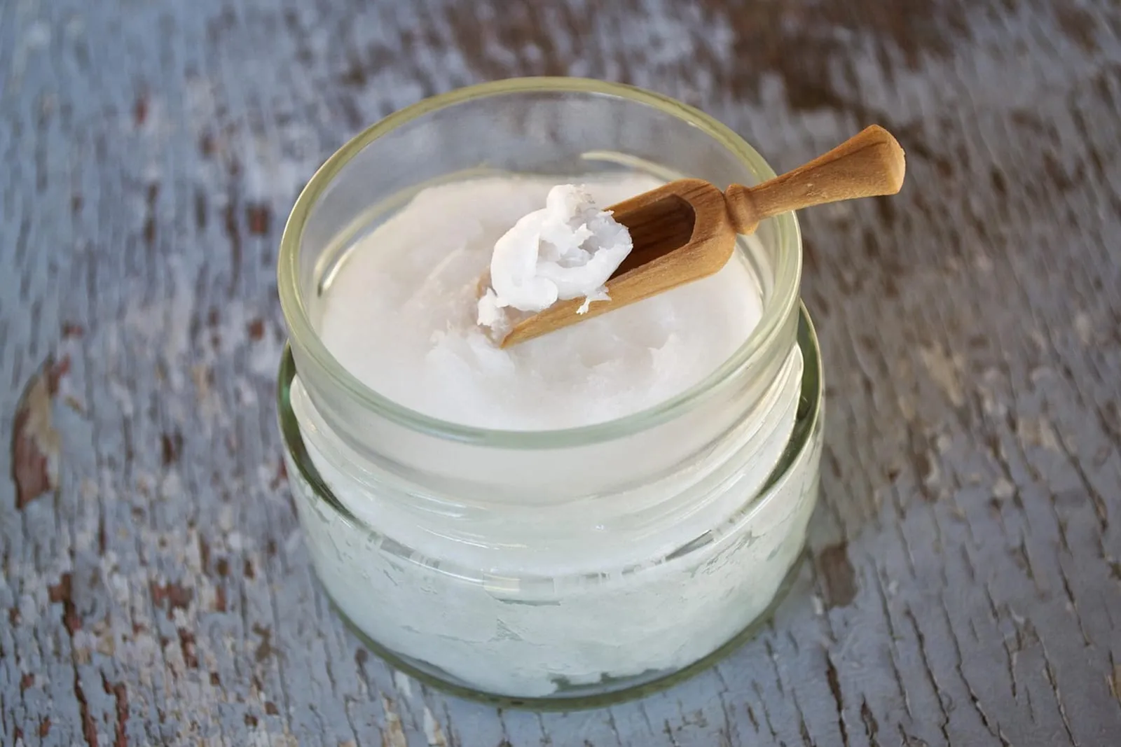 Glass jar of coconut oil with a wooden spoon
