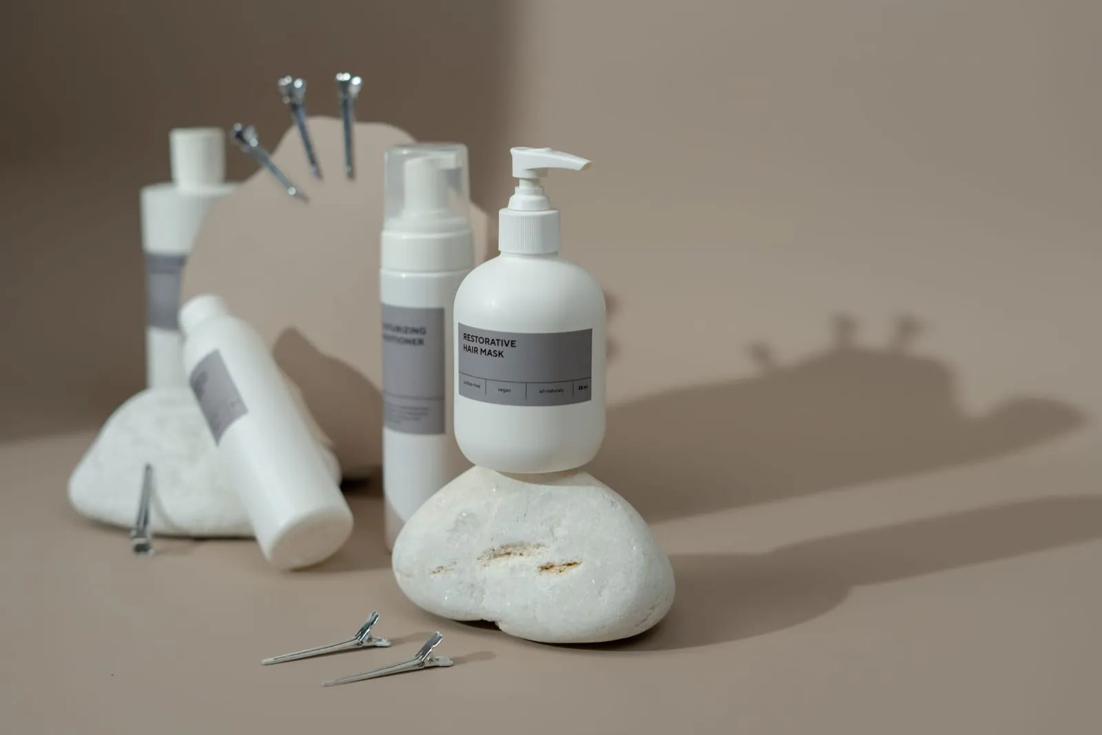 Conditioner, leave-in and styling bottles with sectioning clips on a neutral counter