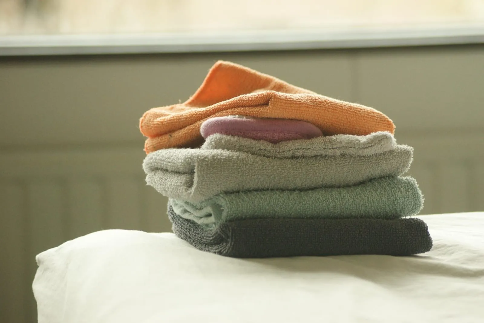 Stack of neatly folded towels on top of a bed