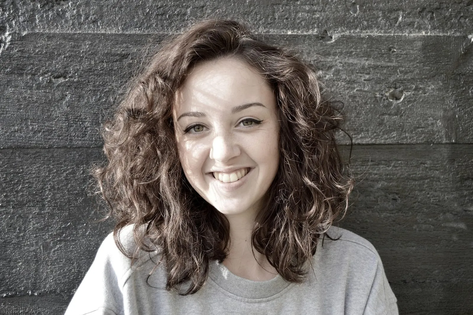 Smiling woman with a short haircut standing against a wall