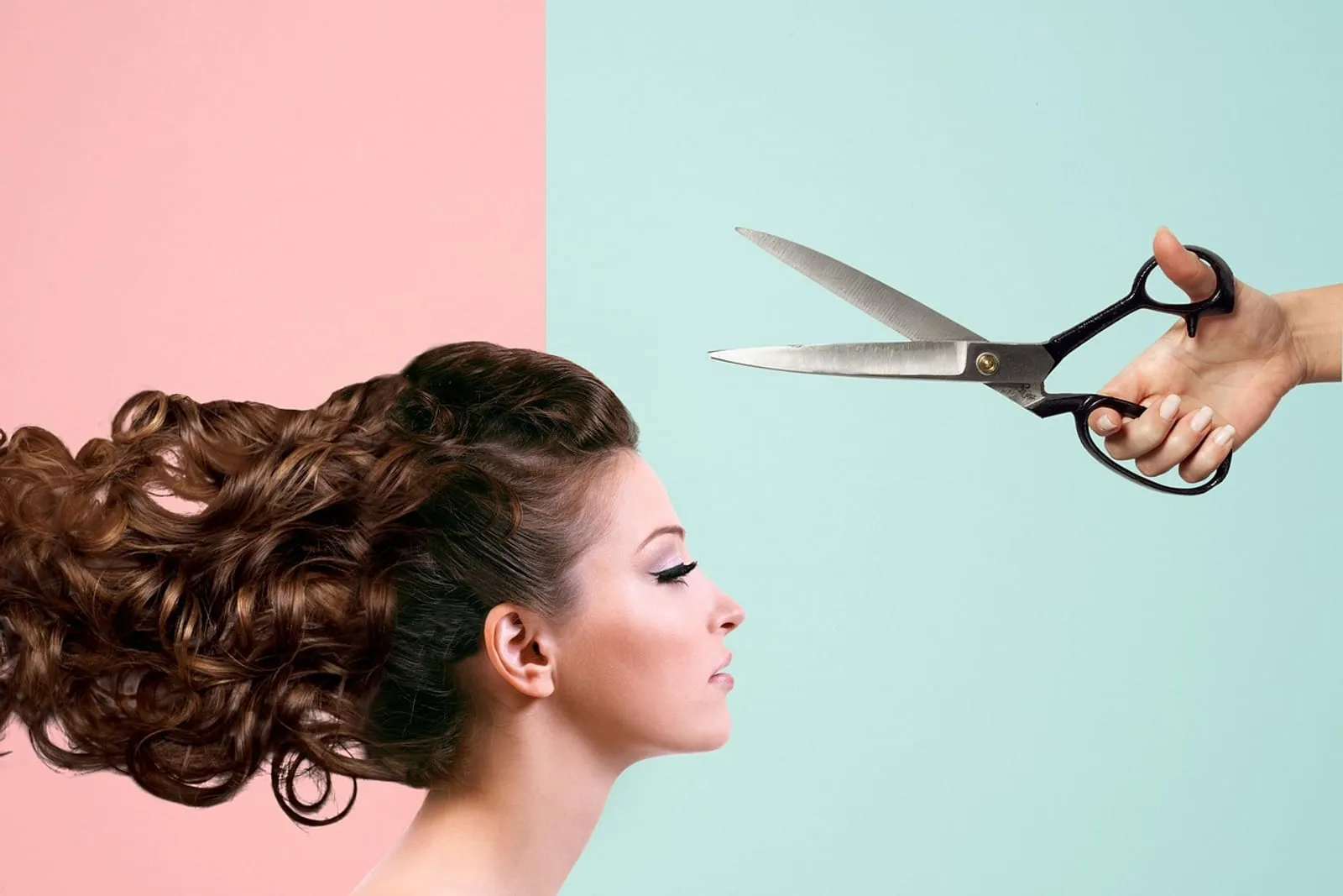 Woman with voluminous curly hair beside a hand holding open scissors