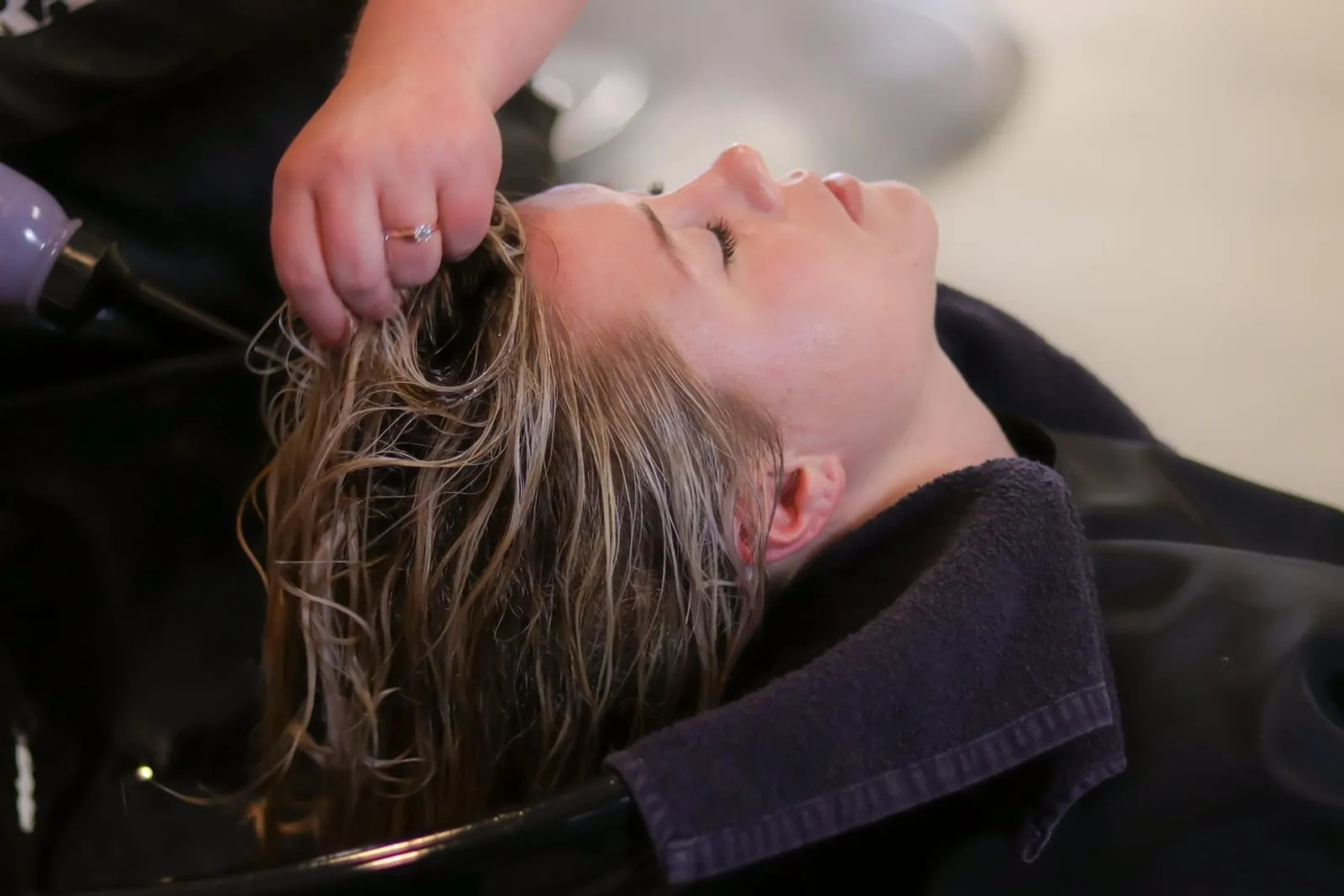 Woman having her hair rinsed at a salon wash basin