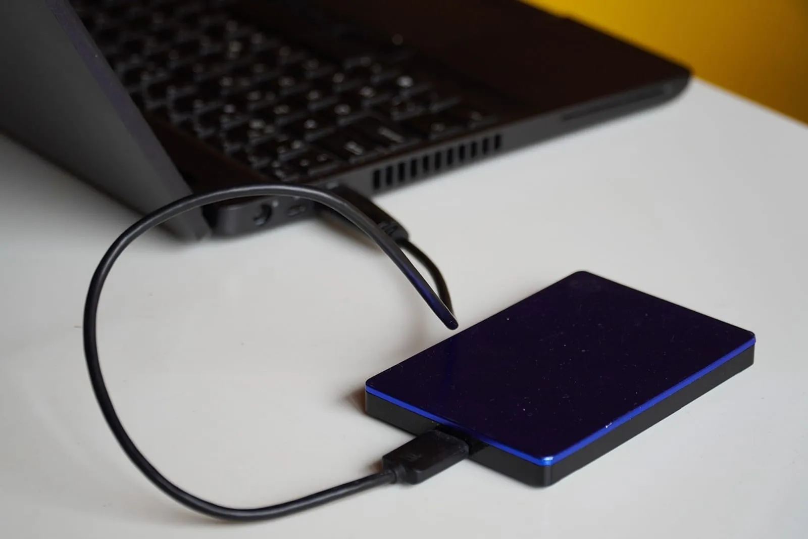 Portable external hard drive connected to a laptop on a desk