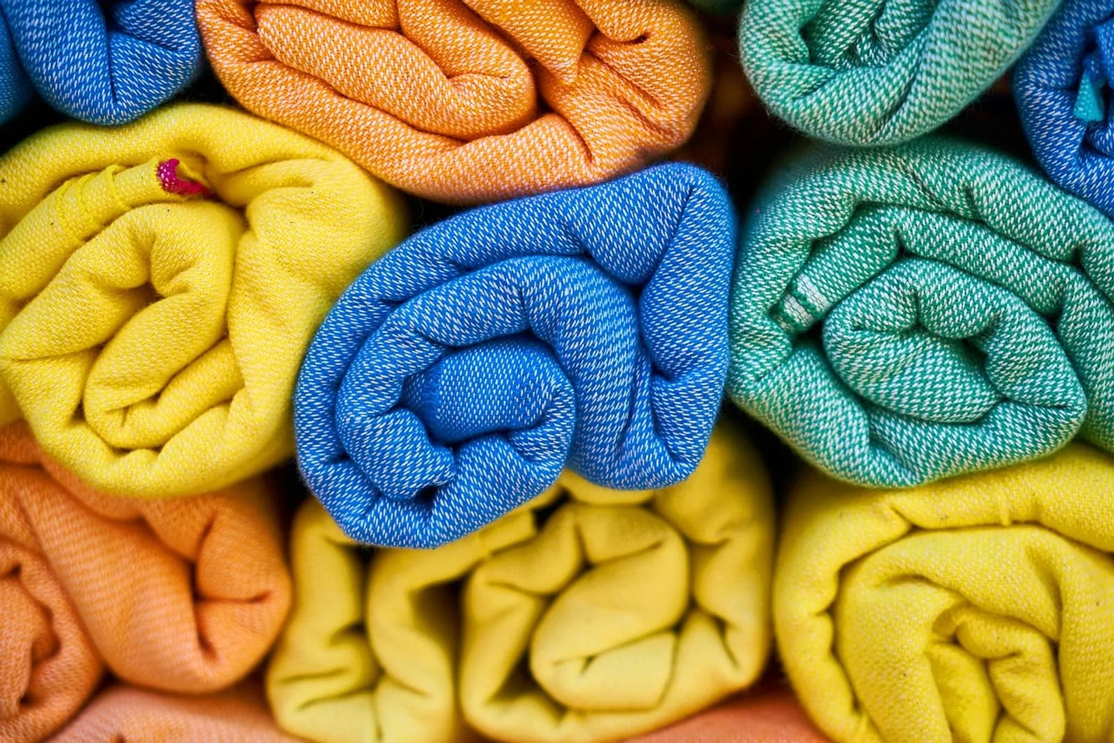 Colorful soft towels rolled up and stacked side by side