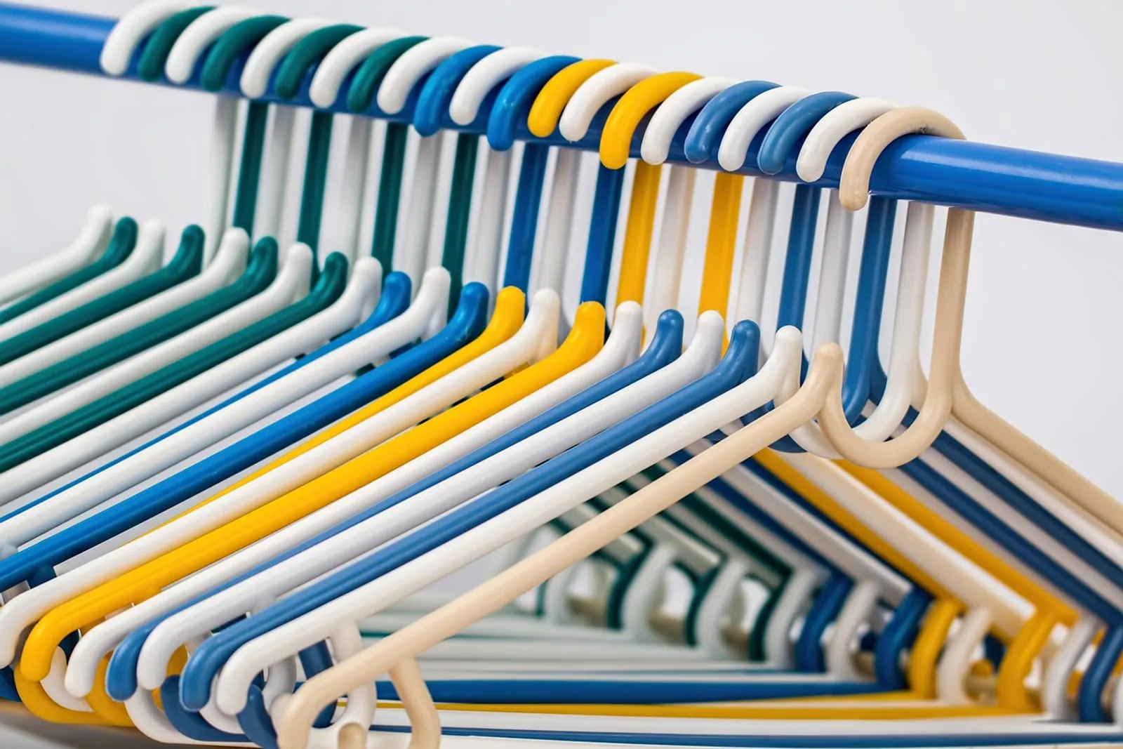 Rows of colorful plastic clothes hangers on a rail