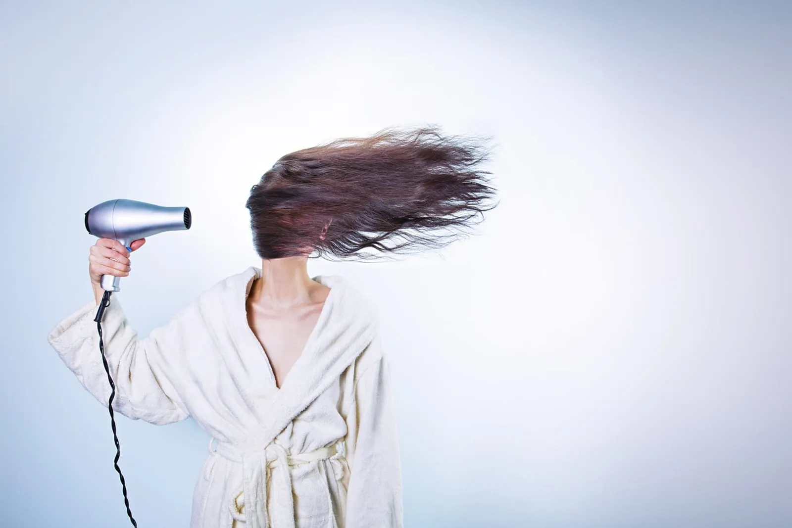 Woman with brunette hair being styled with a hair dryer