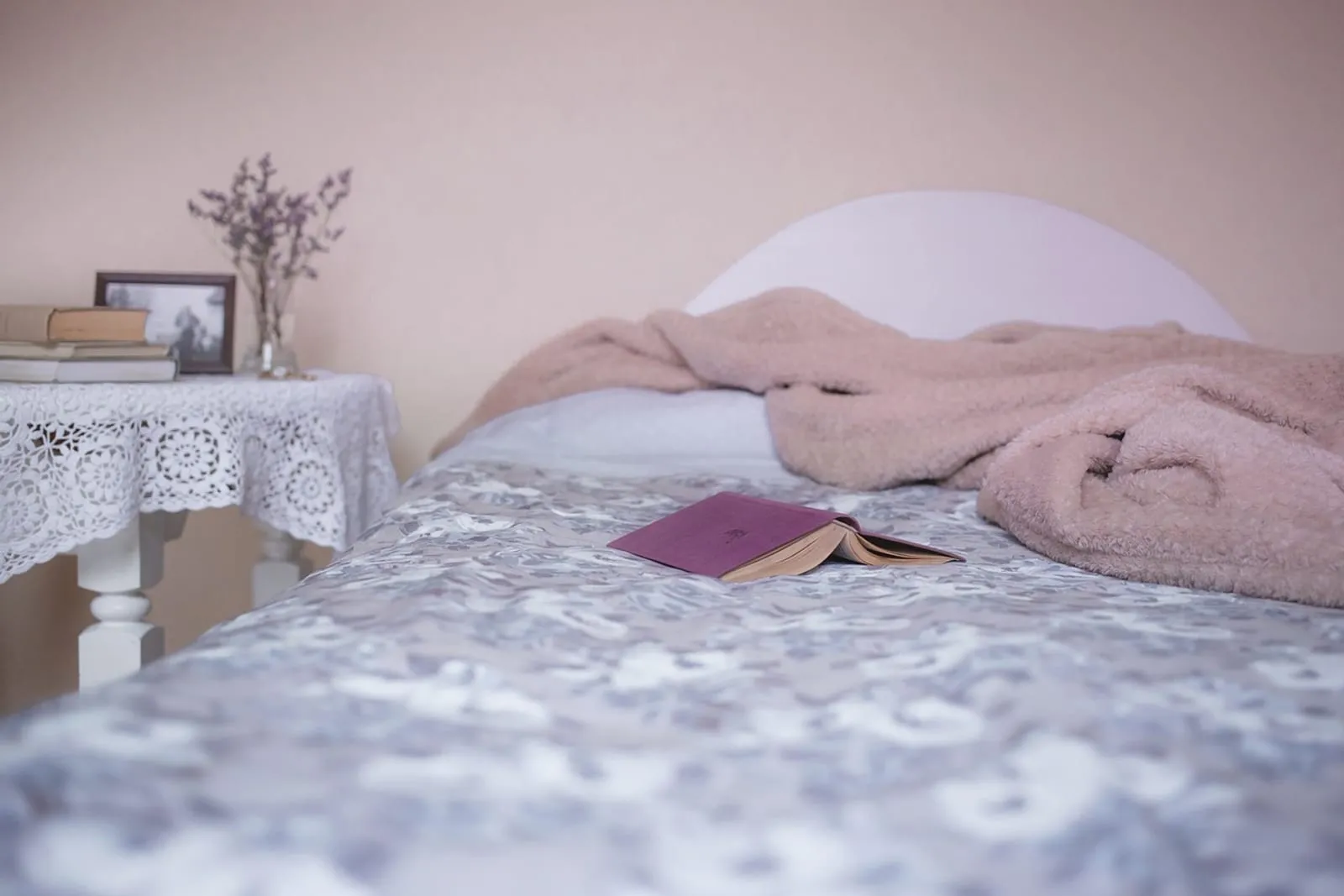 Single bed with a rumpled blanket and a book resting on the covers